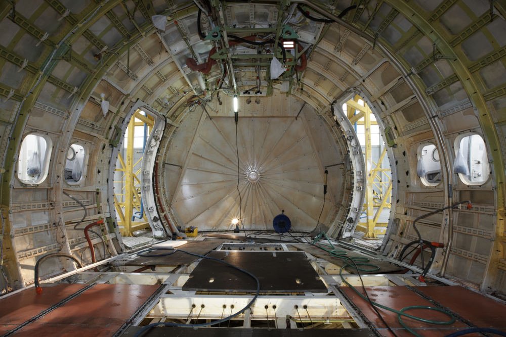 The interior of an airplane stripped of all seats, walls, and insulation as it undergoes maintenance,