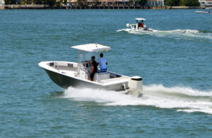 A small fishing boat with an outboard motor is on the foreground with another boat nearby close to the shoreline.