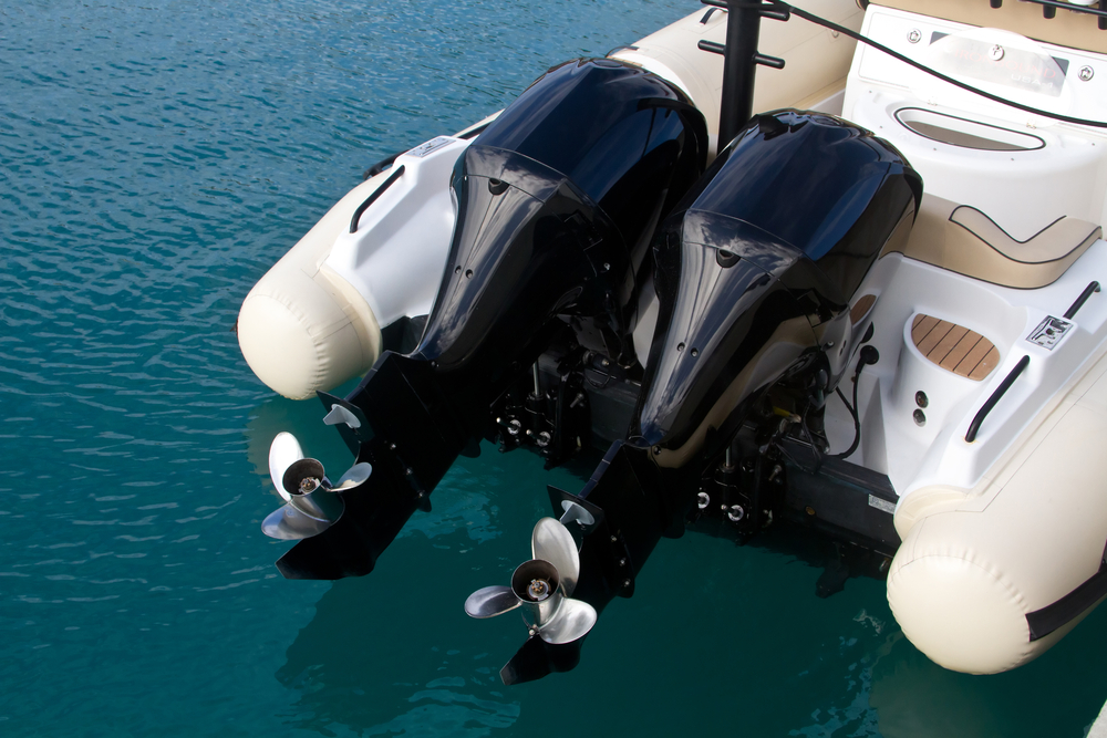 Back end of a boat with dual engines parked in a marina.