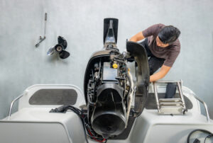 Man removing the outer casing of a boat motor to inspect the equipment.