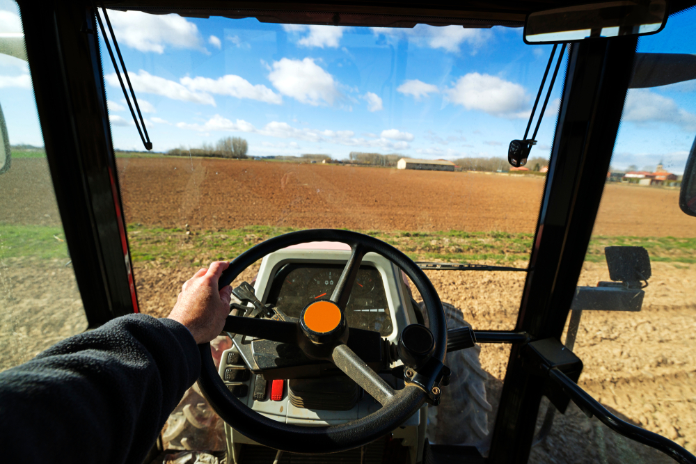 View of a field from inside the cab of a tractor.
