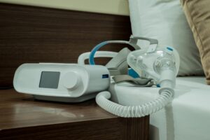 A CPAP machine sits on a bedside table waiting to be used.
