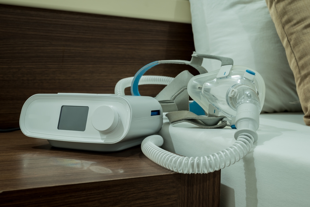 A CPAP machine sits on a bedside table waiting to be used.